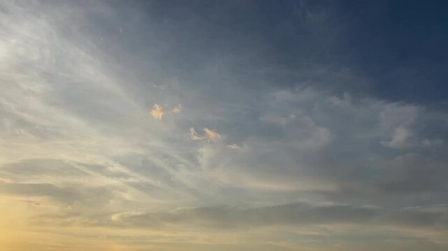 朝焼けの光を反射して淡く染まる白い雲と青空