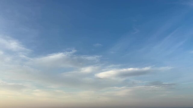 朝焼けの淡い光が差し込む青空と広がる白い雲