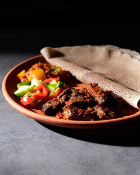 Spicy Beef Stew with Injera and Fresh Salad on Rustic Plate