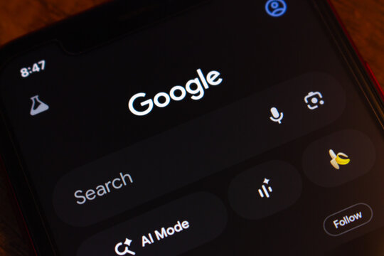 Mexico City, MEXICO - Mar 31 2026 : Close-up of an iPhone displaying the Google Search app in dark mode, showing the search bar, AI Mode shortcut, Google Lens, and voice search icons.
