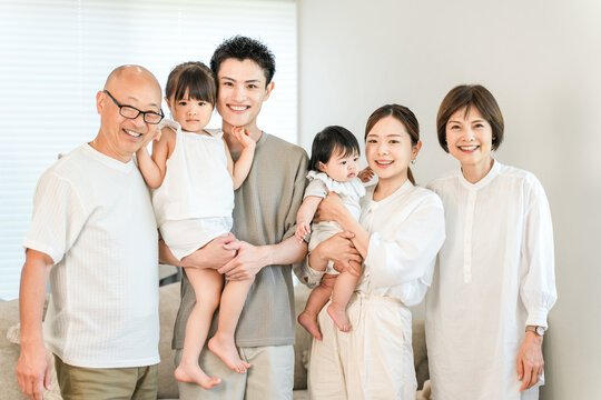 A three-generation family sitting together in the living room of their home.