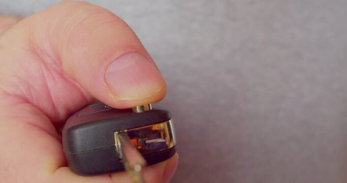 A man's hand opens a folding car key. Close-up