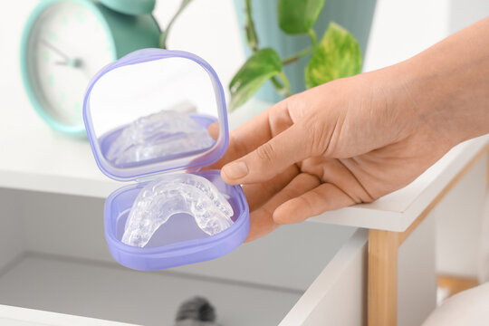 Female hand taking box with occlusal splint from drawer in bedroom, closeup