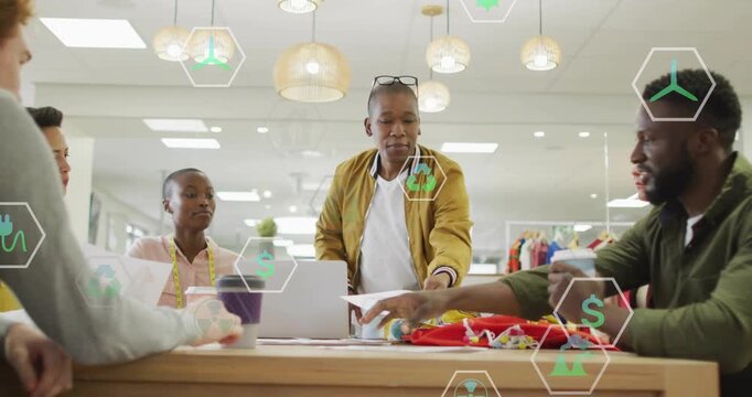 Standing man placing prints and swatches for fashion review, green hex icons annotating laptop