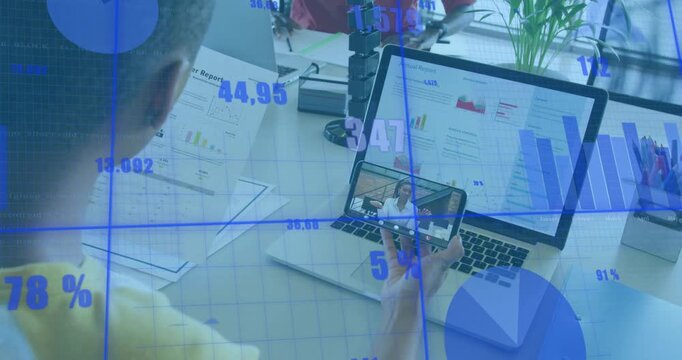 Man in yellow tilting phone over laptop, blue analytics shifting while comparing report with remote