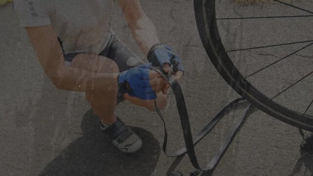 Mature woman kneeling paved road pulling tube following flat tire inspecting valve for bike repair