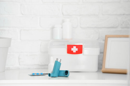 Modern inhalers, pills and first aid kit on chest of drawers, closeup