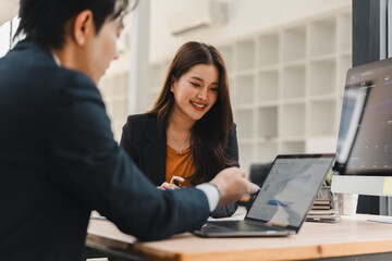 Obraz premium Asian business professionals collaborating on a project using a laptop in a modern office