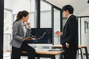 Fototapeta premium Business colleagues analyzing stock market data on a computer screen in a modern office