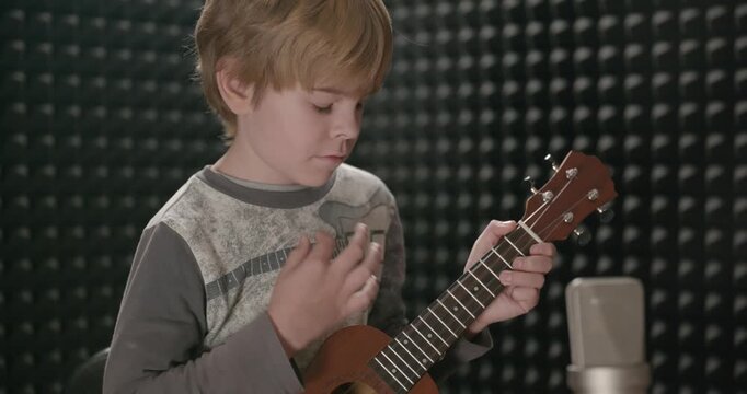 Boy Play Music on Ukulele Instrument in Home Studio. 4K 10-bit