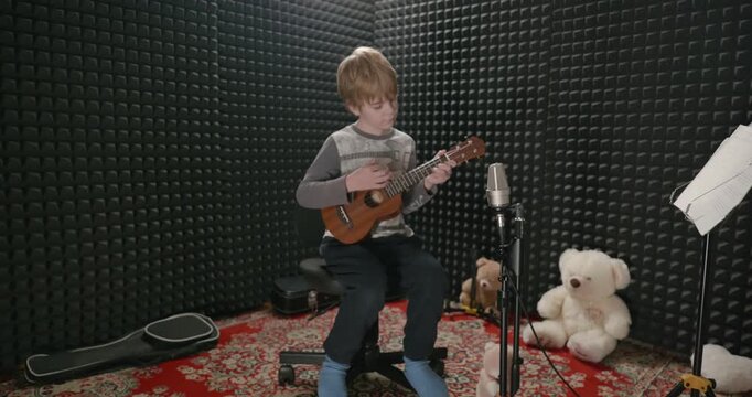 Boy Play Music on Ukulele Instrument in Home Studio. 4K 10-bit