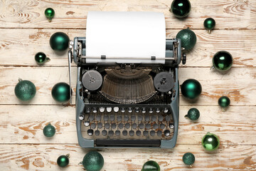 Obraz premium Vintage typewriter with green Christmas balls on white wooden background