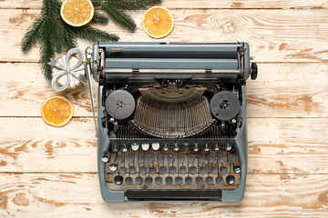 Obraz premium Vintage typewriter with Christmas tree branches, gift box and slices of dried orange on white wooden background