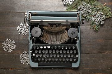 Obraz premium Vintage typewriter with Christmas tree branches and snowflakes on wooden background