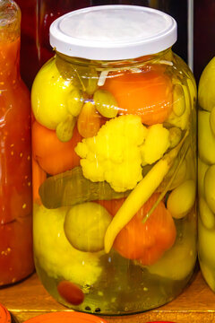Large closed glass jar filled with organic fermented vegetables in home pantry interior
