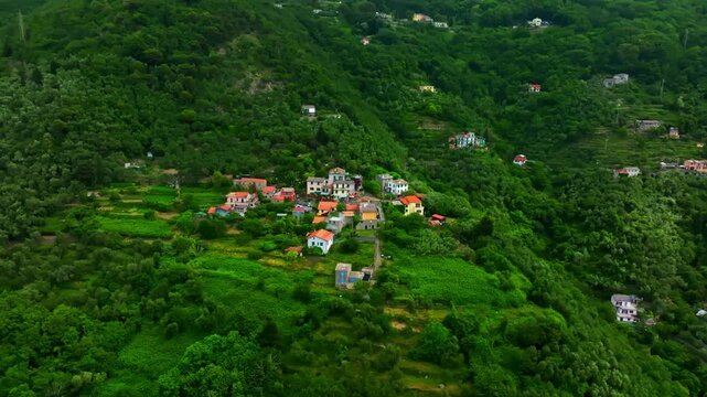 Aerial view circling colorful houses nestled in lush green Ligurian mountains