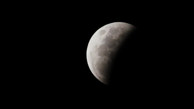 A first quarter moon at night with clear skies and half of the moon covered in light and the other in darkness.