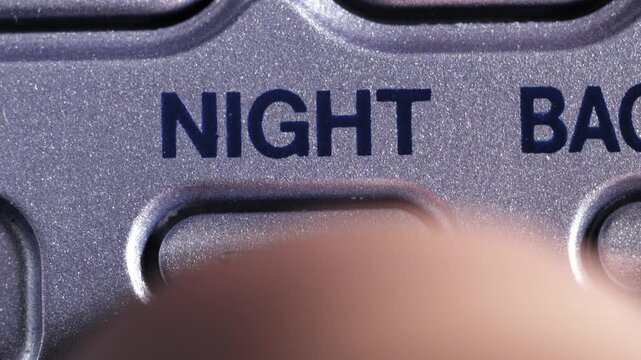 Macro close up of night mode button pressed on metallic blue gray panel