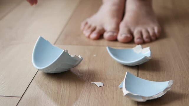 Broken bowl on the floor near bare feet
