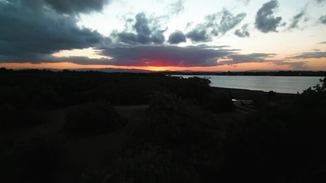 Rising above the trees in the late afternoon to revel a red hot sun on the horizon over the river.