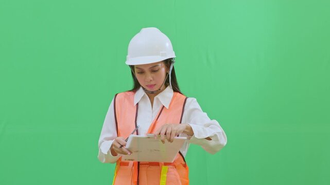 Close-up of a female engineer clipping a new document onto her clipboard. Portraying organization and document management in an industrial setting on green screen.