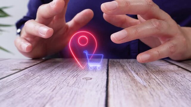 Location-based shopping. Close-up of a pair of hands at a table, shielding a virtual location pin icon and a shopping cart.