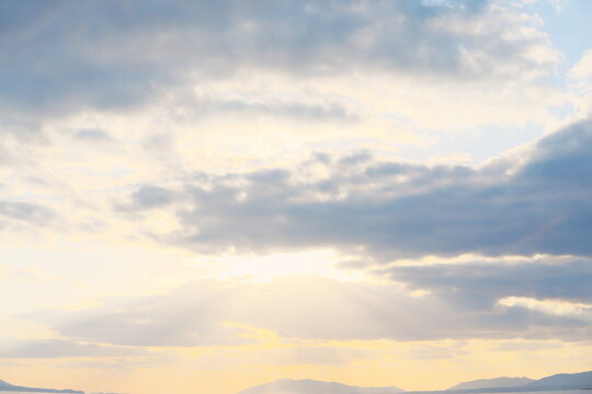 雲の隙間から降り注ぐ薄明光線と夕暮れに染まる静かな山並みの風景