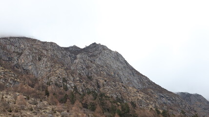 Fototapeta premium A high-angle, wide shot of a rugged, rocky mountain peak under a bright, overcast sky