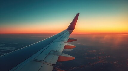 Obraz premium Airplane wing extends gracefully into a breathtaking sunset or sunrise sky, painting the horizon with magnificent hues.