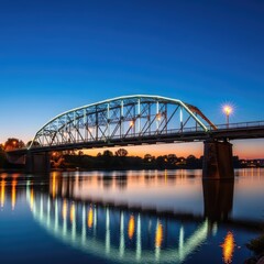 Fototapeta premium Bright electric lights outline a steel bridge structure over a calm river during twilight, creating vibrant reflections on the water surface, modern, engineering, calm