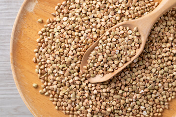 Obraz premium Raw organic buckwheat seeds in a wooden spoon, Food ingredient, Top view