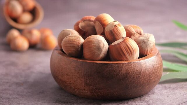 Man hand picking up hazelnuts from wooden bowl close up slow motion macro shot.