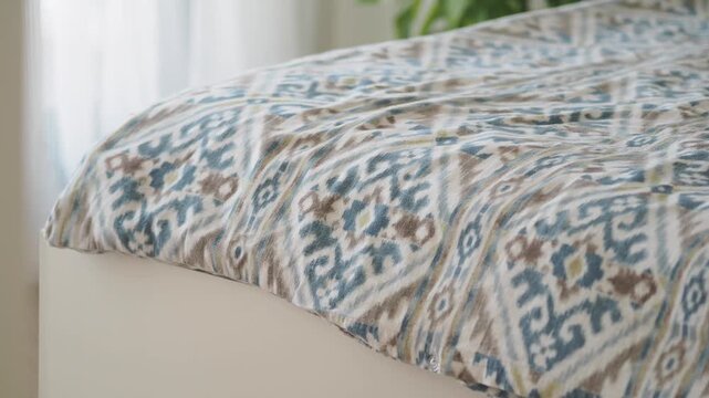 Cozy patterned duvet cover gently moving on soft bed with natural light indoors.