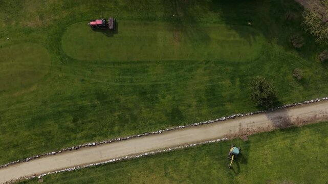 Aerial view of mowing machines maintaining golf course grass, showing professional lawn care and precision turf management.