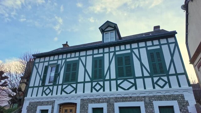 View of a traditional half-timbered house with green shutters, typical of the architecture in Etretat, Normandy, France