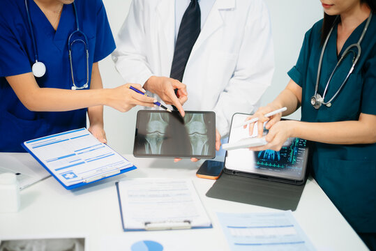 Doctors and nurses analyzing x-ray image on tablet for diagnosis, using digital technology in modern hospital, teamwork