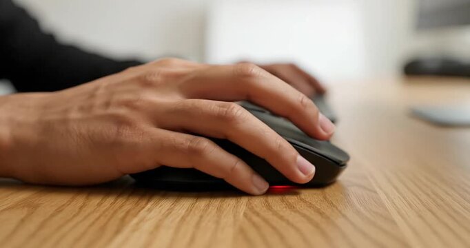 Close-up of a hand using a computer mouse on a wooden desk with a blurred background (1)