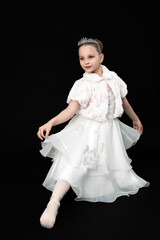 Charming little girl poses in white dress, tiara and fur bolero. Ballerina looks like princess. Elegant, graceful and innocent mood. Black studio background © Alexander Piragis