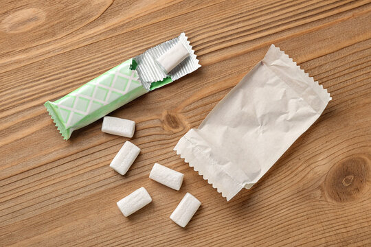 Chewing gum pieces with wrapper on wooden background