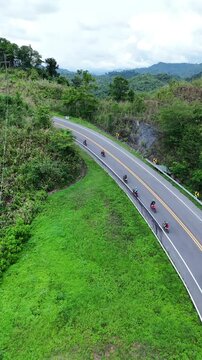 Winding Road Through Lush Green Hills Motorcyclists Enjoy Scenic Ride on Curving Mountain Path with Power Lines and Adventure
