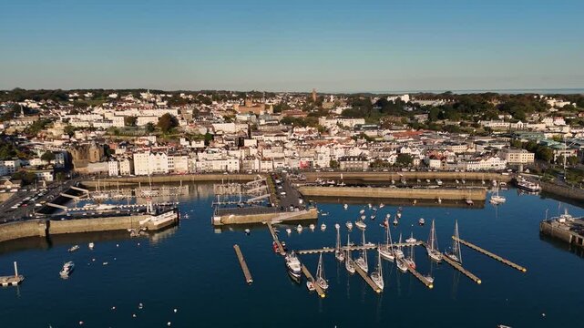 St Peter Port Harbour Guernsey very high reveal drone footage of St Peter Port harbour,outer pontoon moorings , the pool and extensive views across St Peter Port in late afternoon sun on clear day