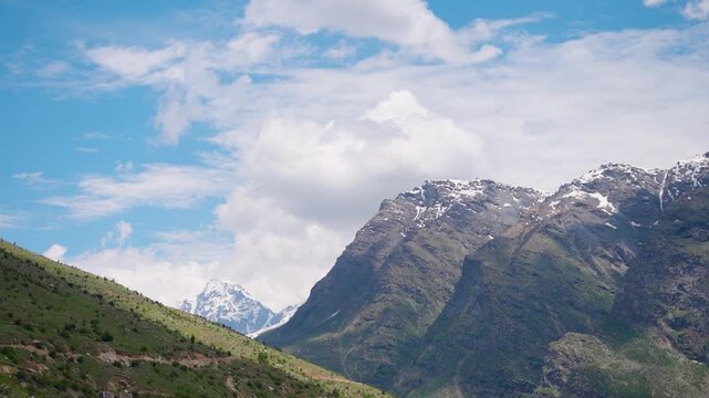 4K Landscape shot of clouds above the Himalayan mountain range with snowy peaks during the summer season as seen from Marbal village in Lahaul Valley, Himachal Pradesh, India. Scenic Background.