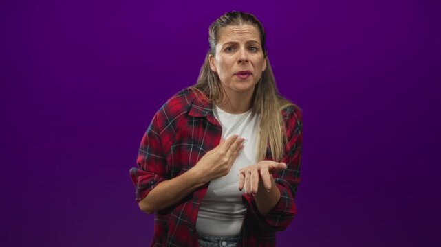 Woman in red plaid shirt makes pinched fingers gesture with open palm, hand visible, studio; concern questioning appeal.