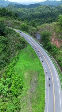 Aerial View of Winding Road Through Lush Green Mountains and Hills with Vehicles and Motorcyclists Enjoying Scenic Adventure and Beauty