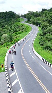 Group of Motorcyclists Riding Along Winding Road Through Lush Green Hills Enjoying Scenic Journey