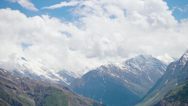4K shot of clouds above the snow covered Himalayan mountain peaks as seen from Marbal village during the summer season in Lahaul and Spiti district, Himachal Pradesh, India. Scenic Natural background.