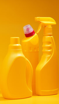 Cleaning supplies arranged together on a yellow background showcasing their bright colors