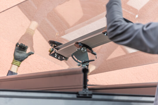 Workers install patio roofing with steel and glass