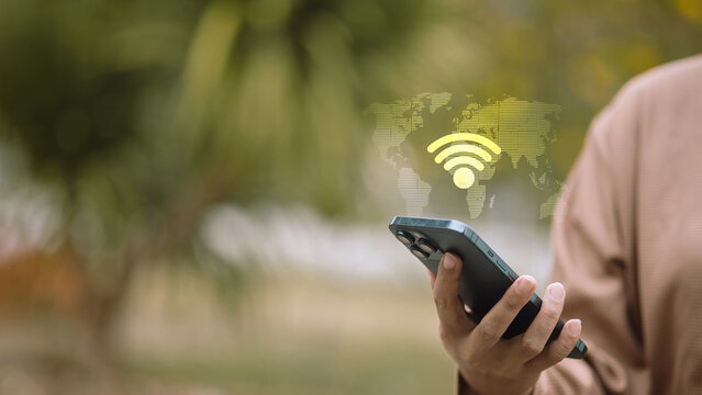 Person holding smartphone with global wifi connection icon and world map overlay outdoors.