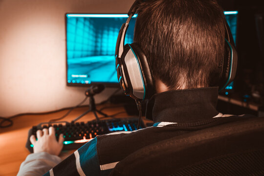 Teenager in headphones playing video game on his computer